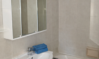 A modern bathroom with a bathtub and a sink. The walls are decorated with bright tiles and blue floral patterns.