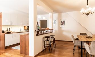 A modern kitchen with an open dining area and elegant furniture. The wooden floor creates a warm atmosphere.