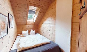A cozy bedroom with wood paneling and a skylight. The beds are simply furnished and invite relaxation.