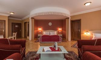 An elegant room with a red sofa and a large bed. The walls are painted in soft tones and there is cozy lighting.