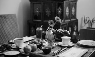 A beautifully set table with various breakfast dishes, including fruit, coffee, and juices. In the background, there is a decorative chest.