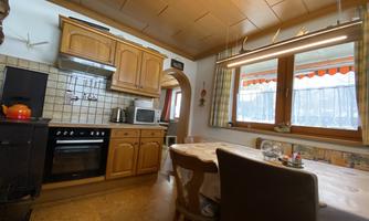 A cozy kitchen with wooden cabinets and a dining table. The window lets in plenty of daylight and offers a view outside.