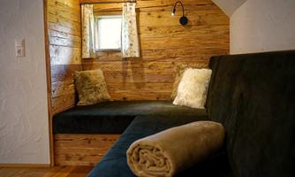 A cozy interior with wooden paneling and a seating area. In the corner lies a beige towel and there are two cushions on the bench.