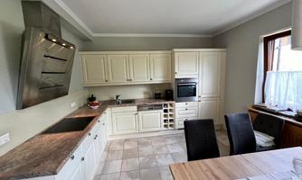 A modern kitchen with bright cabinets and wooden surfaces. The room is well-lit and offers space for a dining table.