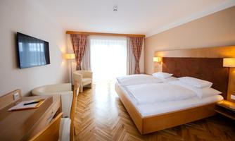 Bedroom with two beds and hardwood floor. There is a television and a window with curtains.