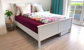 Friendly bedroom with a white double bed, colorful bed linen, and direct access to the balcony.