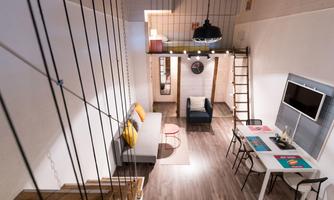 A modern, bright living room with a cozy atmosphere. There is a staircase, a dining table, and seating in the room.