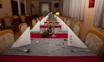 An elegantly set table in a restaurant with gray and red tablecloths. The table is decorated with cutlery, napkins, and flowers.