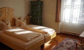 A cozy bedroom with two beds and wooden floors. The room has plenty of daylight and a rustic atmosphere.
