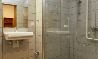 A modern bathroom with a glass shower and clear tiles. The sink is also designed to be simple and functional.