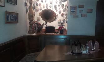 A cozy room with a table and a bench. 

On the wall, there are pictures and an old gramophone.
