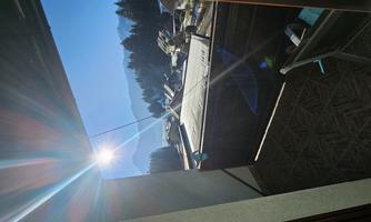 A sunny balcony with a view of the mountains and a valley. The clear air and nature create a peaceful atmosphere.