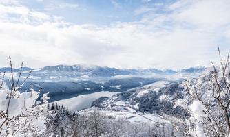 A snowy landscape with mountains and a calm river. The sky is bright and clear.