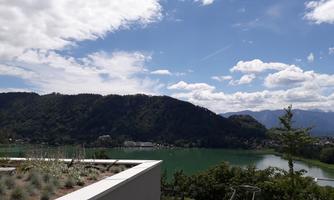 A picturesque view of a lake surrounded by mountains. The sky is partly cloudy with some sunshine.