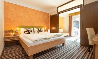A modern room with a double bed and a cozy single bed. The warm colors and clear design create an inviting atmosphere.