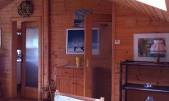 A wooden interior with a warm, inviting feel. The room is bright and has a cozy atmosphere with various pieces of furniture.