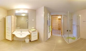 A modern bathroom with bright tiles and a glass shower. The furnishings include a sink and storage in a wood look.