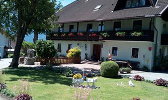 A charming house with a balcony and colorful flower boxes. The well-maintained garden is adorned with various plants and decorative figures.