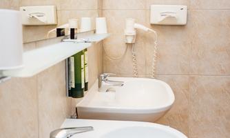 A modern bathroom with two sinks and a large mirror.  
Bright tiles and windows create an open and inviting atmosphere.