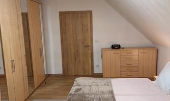 A cozy bedroom with a double bed and a modern wardrobe. The wooden floor and warm colors create an inviting atmosphere.
