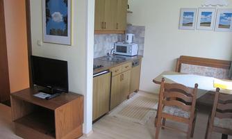 A cozy kitchen with a dining table and chairs. In the background, kitchen cabinets and appliances are visible.