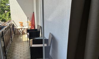 A bright balcony with a glass table and modern chairs. Overlooking our castle ruin and many trees.