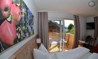 A cozy room with a magnificent view of a balcony. A picture of red apples hangs on the wall, creating an inviting atmosphere.