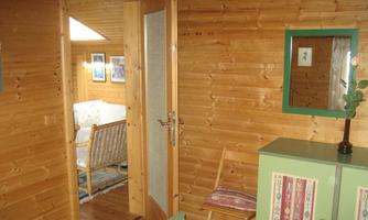 A cozy room with wooden paneling and an open door. A chair and a green cupboard are visible.