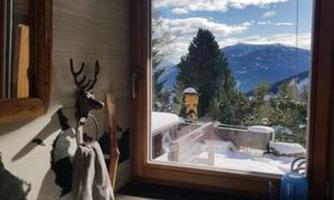 A bathroom with a sink and a large window. Through the window, you can see snow-covered mountains and a clear sky.