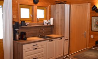 A cozy wooden kitchen with modern appliances and plenty of storage space. The large windows let in a lot of light and give the kitchen a friendly atmosphere.