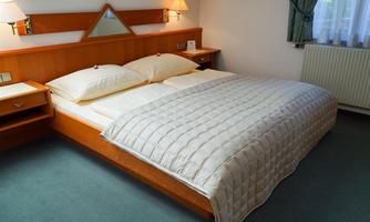 A cozy bedroom with a large double bed and two nightstands. The walls are painted in soft colors, and a window lets in natural light.