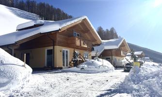 A wonderful winter landscape with wooden chalets and fresh snow. The sun shines brightly in the blue sky.