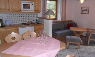 A cozy living space with a kitchenette made of light wood. The table is beautifully set and the atmosphere is inviting.