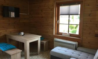 A cozy living space with wooden paneling. There is a table, a couch, and a window with a view outside.