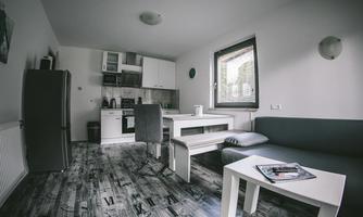 A modern apartment with an open kitchen and a cozy living area. Bright walls and hardwood floors create an inviting atmosphere.