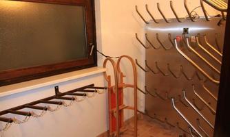 A clean room with wall hooks for clothing and a shoe rack. The window provides natural light.