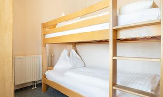 A simple room with a wooden bunk bed. The bedding is clean and tidy, the room feels bright and inviting.