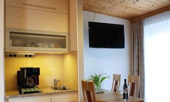 A modern kitchen with a dining area and a large window. On the countertop, there is a coffee machine and a small plant.