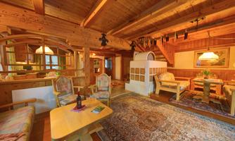 A cozy living room with wooden furniture and a warm ambiance. The room is decorated with a rug and a small table.