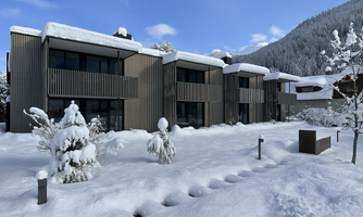 A modern building in the snow with snow-covered trees and a clear blue sky. The tranquil winter landscape conveys a peaceful atmosphere.