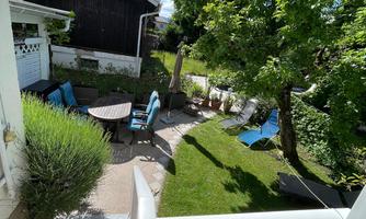 A beautiful garden with an apple tree, lawn with loungers and seating areas.