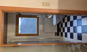 A modern bathroom with a shower area and a window. The floor is designed with black and white tiles.