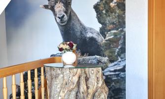 An impressive mural of a chamois in a natural environment. Accompanied by a rustic log table and a small stool.