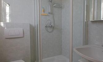A modern bathroom with a shower enclosure, a sink, and a toilet. The bright tiles create a clean and inviting atmosphere.