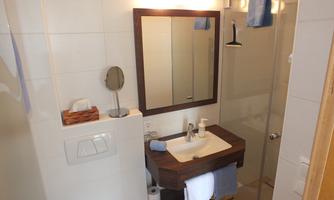 A modern bathroom with a shower and a sink. The room is bright and well-equipped.