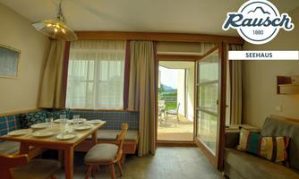 A cozy living space with a dining table and chairs. Large windows offer a view of the terrace and the surroundings.