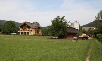 A rural scene with two farmhouses and meadows. In the background, gentle hills and trees can be seen.