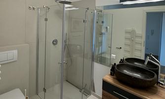 A modern bathroom with a glass shower and a stylish sink. The walls are bright and the floor is neutrally designed.