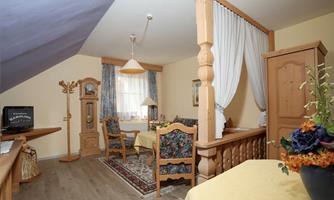 A cozy room with wooden decor and a table. On the walls, there are windows with curtains and a clock.