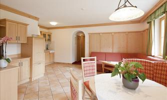 A cozy living kitchen with bright wood interiors and a large dining table. The well-maintained furnishings create an inviting atmosphere.